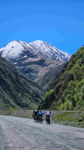 Riders climbing gravel road Juta Valley bike tour Kazbegi