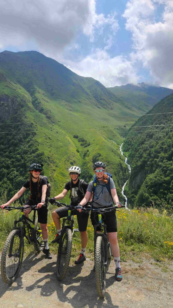 Mountain bikers on the trail in Juta Valley with green alpine slopes, Georgia