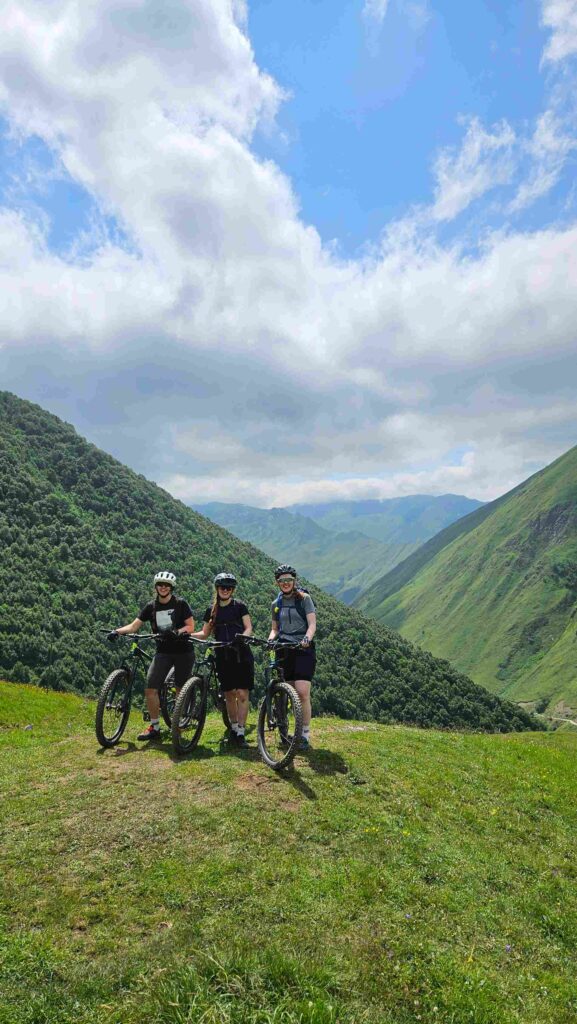 Mountain bikers climbing above Juta Valley on a sunny day, Greater Caucasus, Georgia