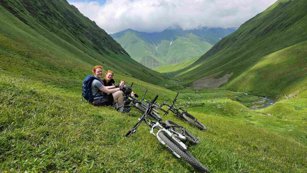 Taking a quick rest break on the grassy mountain slopes with an incredible backdrop.