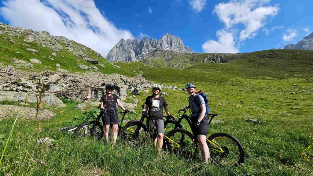 The Norwegian team posing with their bikes in front of the dramatic Chaukhi Massif peaks.