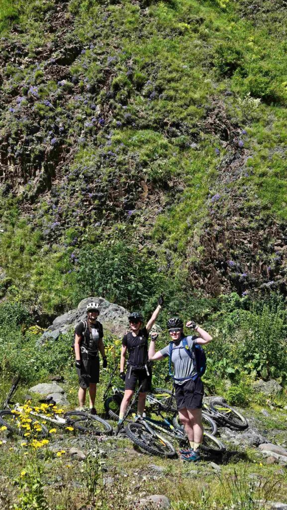 Group of three riders resting by a cliff with wildflowers, Gudamakari Valley, Georgia