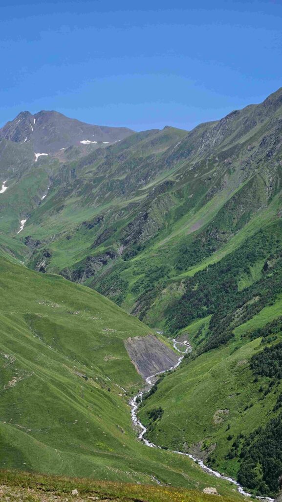 Alpine meadow below a rocky Caucasus summit on the Gudamakari MTB route