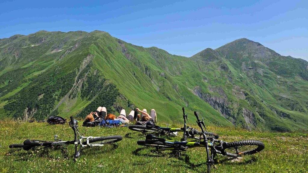 Three riders on the alpine meadow above Gudamakari Valley — the kind of view that makes people book a flight back next year.