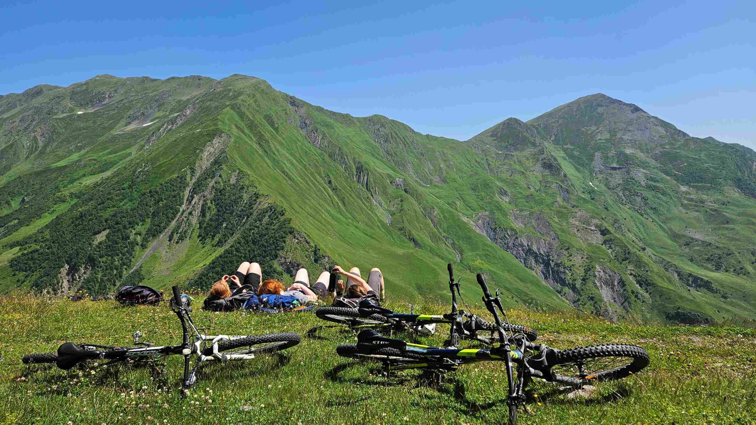 Three riders on the alpine meadow above Gudamakari Valley — the kind of view that makes people book a flight back next year.
