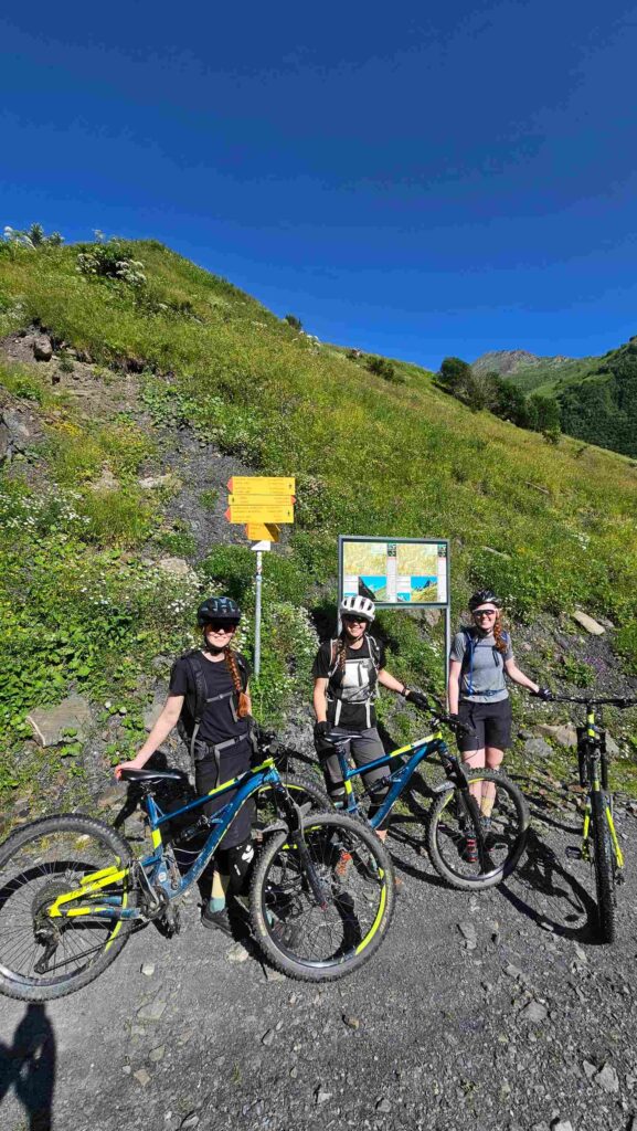 Three riders at a trail information board at the end of the Gudamakari Valley MTB route